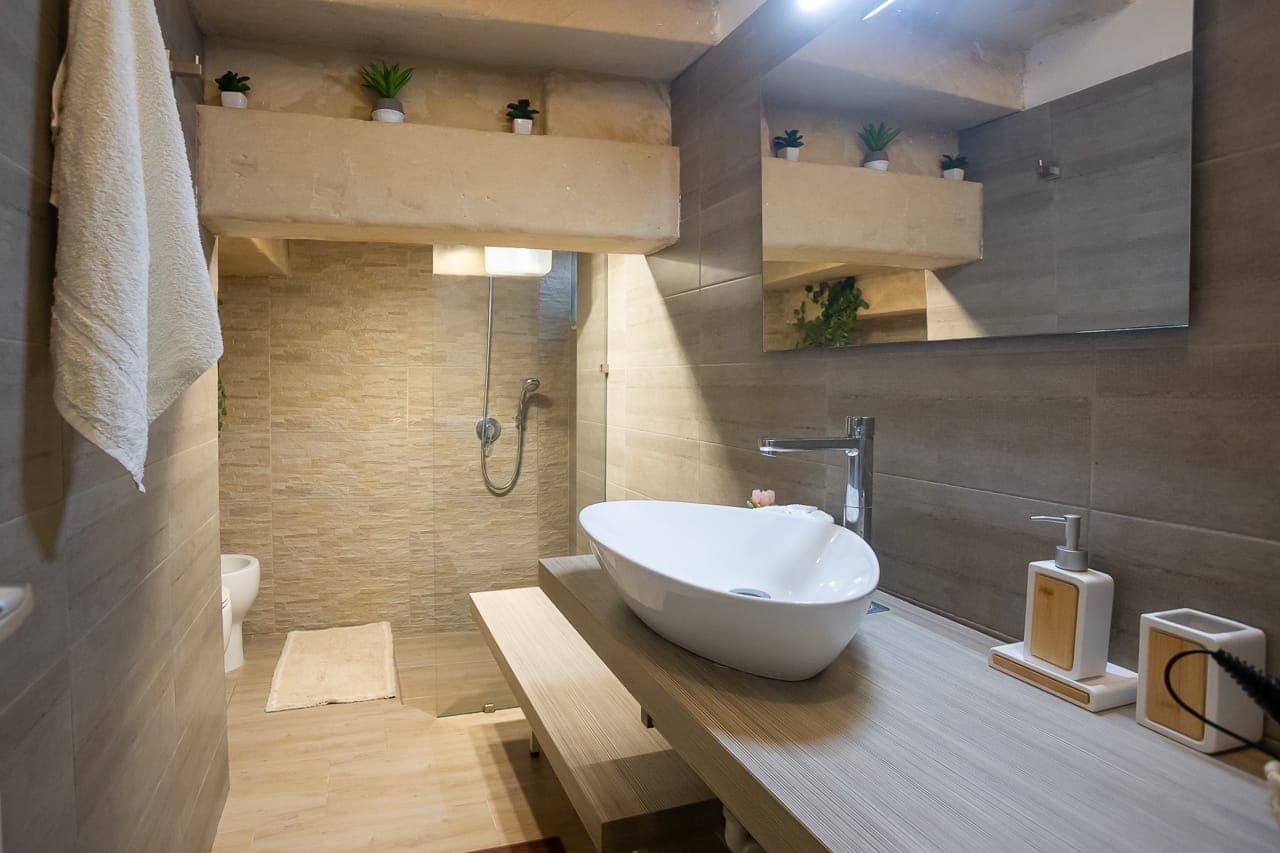 Bagno rivestito in pietra con doccia walk-in e lavabo d'appoggio